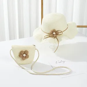 Dettaglio del cappello di paglia e borsa a tracolla coordinata con decorazioni floreali