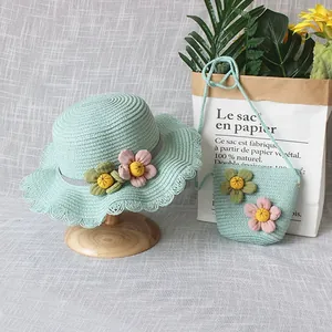 Détail d'un chapeau de paille vert menthe avec fleurs en tissu et petit sac assorti pour filles