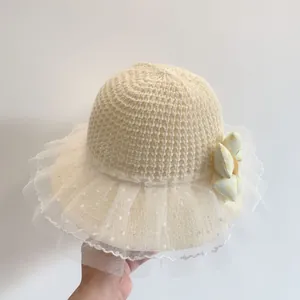 Detail of children's straw hat with mesh knit texture and polka dot lace flower trim