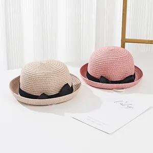 Elegant children straw hats in beige and pink with decorative black ribbon bows for sun protection