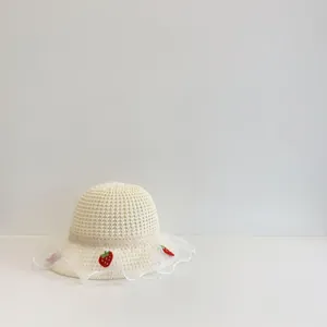 Detail van strooien zonnehoed met fijne kanten rand en schattig rood aardbeienborduurwerk