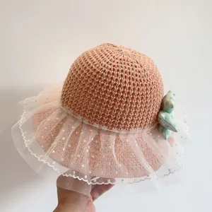 Detail of a pink straw sun hat for girls with white polka dot mesh and a green bow