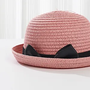 Detail of pink straw sun hat featuring a black grosgrain ribbon with a stylish bow