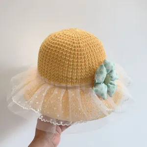 Detail of yellow crochet straw hat with white lace trim and green polka dot flower