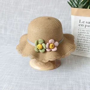 Détail d'un chapeau de paille pour enfants avec bords ondulés et fleurs décoratives