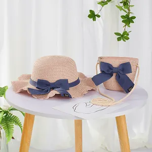 Detailed close-up of pink straw hat and matching mini bag with dark blue bows
