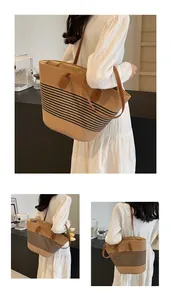 Detail van strooien shopper met zwarte strepen en dubbele bruine lederen handvatten