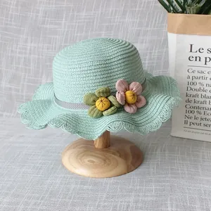 Détail d'un chapeau de paille vert menthe pour filles avec fleurs et bords ondulés