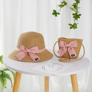 Detailed view of handmade woven straw hat and matching crossbody bag with pink ribbon bows