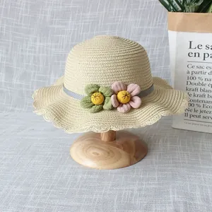 Détail d'un chapeau de paille pour enfant avec bord ondulé et décor floral