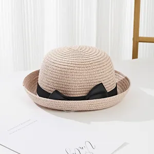 Close-up of fine straw weave texture and elegant black satin ribbon bow on sun hat