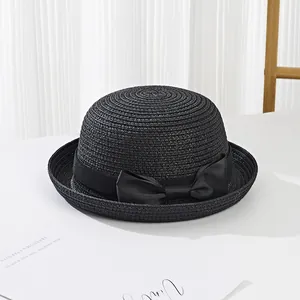 Close-up of black straw sun hat featuring a woven texture and decorative grosgrain bow