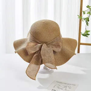 Macro view of woven straw sun hat featuring elegant wavy brim and oversized bow detail