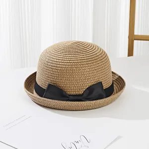 Detailed shot of kids straw hat featuring a chic black ribbon bow and woven texture