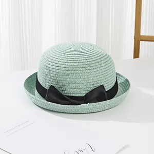 Detail of light green woven straw hat with elegant black grosgrain ribbon bow decoration
