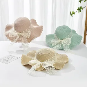 Summer wide-brimmed straw sun hats with lace bows in pink, mint green, and beige colors