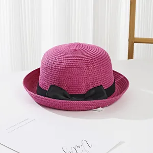 Detail of hot pink straw hat featuring fine spiral weave texture and a black ribbon bow