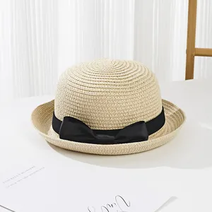 Close-up of kids straw sun hat with black ribbon bow on a clean white surface