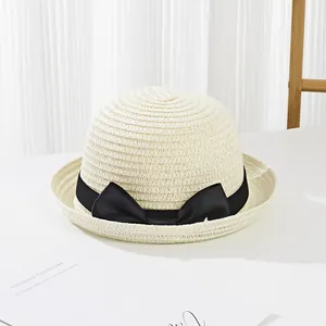 Close-up of cream children straw hat featuring a chic black ribbon bow and woven texture