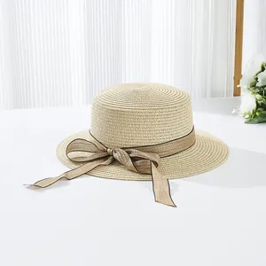 Détail d'un chapeau de paille d'été avec ruban beige, nœud et design élégant à dessus plat