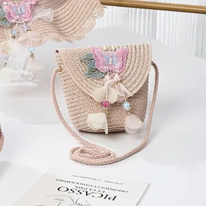 Detail of child straw crossbody bag with pink butterfly embroidery and floral tassel charm