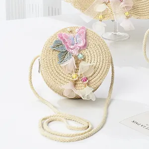 Detail of straw woven kids purse with sequin butterfly embroidery and flower tassels