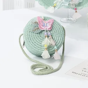 Detail of mint green straw bag with embroidered butterfly and beaded floral tassels