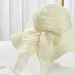 Detail of elegant cream straw sun hat with wide wavy brim and large mesh bow