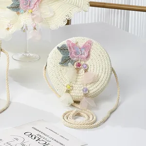 Detailed view of handmade woven straw bag with pink butterfly and petal tassel