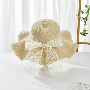 Detailed view of straw hat texture with elegant white lace ribbon bow and wavy brim