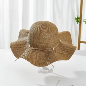 Elegant wide-brim straw sun hat with wavy edge and pearl bow detail for women's beach holiday