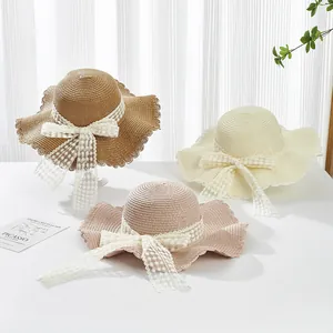 Detail of straw sun hats with wave patterns and elegant white lace bow accents