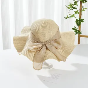 Close-up of beige woven straw hat with a large bow detail and elegant texture