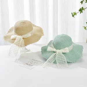 Close-up of woven straw sun hats with wavy edges and decorative lace flower bows