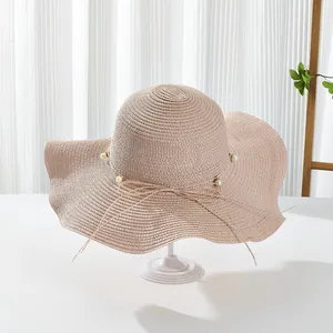 Detail of elegant pink straw sun hat with pearls and a delicate bow for summer vacation