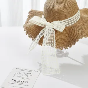 Detailed view of woven straw sun hat featuring elegant white lace floral ribbon bow