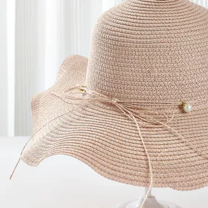 Detailed macro view of beige straw hat featuring elegant pearl accents and bow decoration