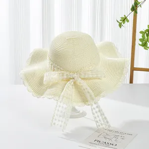 Close-up of cream straw hat featuring detailed lace ribbon with floral embroidery