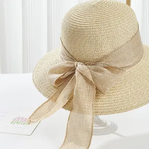 Detail of elegant beige sun hat showing fine straw weave and large linen bow tie