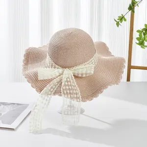 Detailed pink straw hat with wide wavy brim, delicate floral lace and a large bow tie