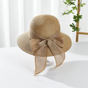 Detail of a natural woven straw sun hat with a large decorative bow for summer