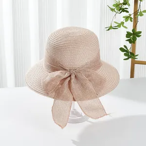 Detail of light pink woven sun hat featuring a large mesh bow and textured spiral weave
