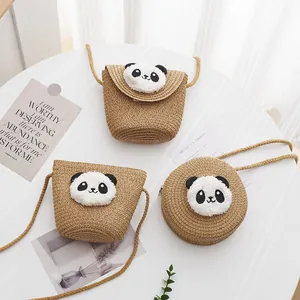Detalle de bolsos bandolera de paja para niños con decoración de panda de felpa suave