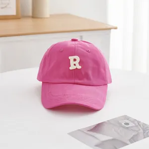 Detailansicht der rosaroten Baumwollkappe mit weißem R-Buchstaben-Stickmuster