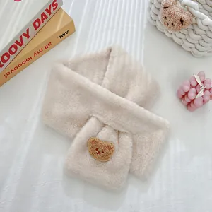 Close-up of beige plush scarf featuring cute brown bear embroidery detail and soft texture