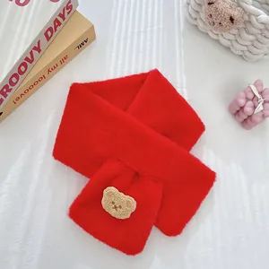 Close-up of a red plush faux fur scarf featuring a cute brown bear patch and cross design