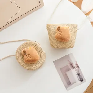 Detail of two woven straw crossbody bags for kids featuring cute plush capybara bear faces