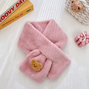Detailed close-up of a pink plush scarf with a cute brown bear patch and cross design