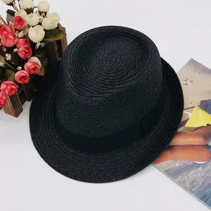Close-up of black straw fedora hat featuring a matching wide ribbon and woven texture
