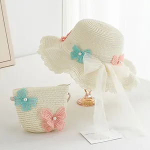 Detailed view of woven straw hat and matching bag with lace butterfly accents and pearls